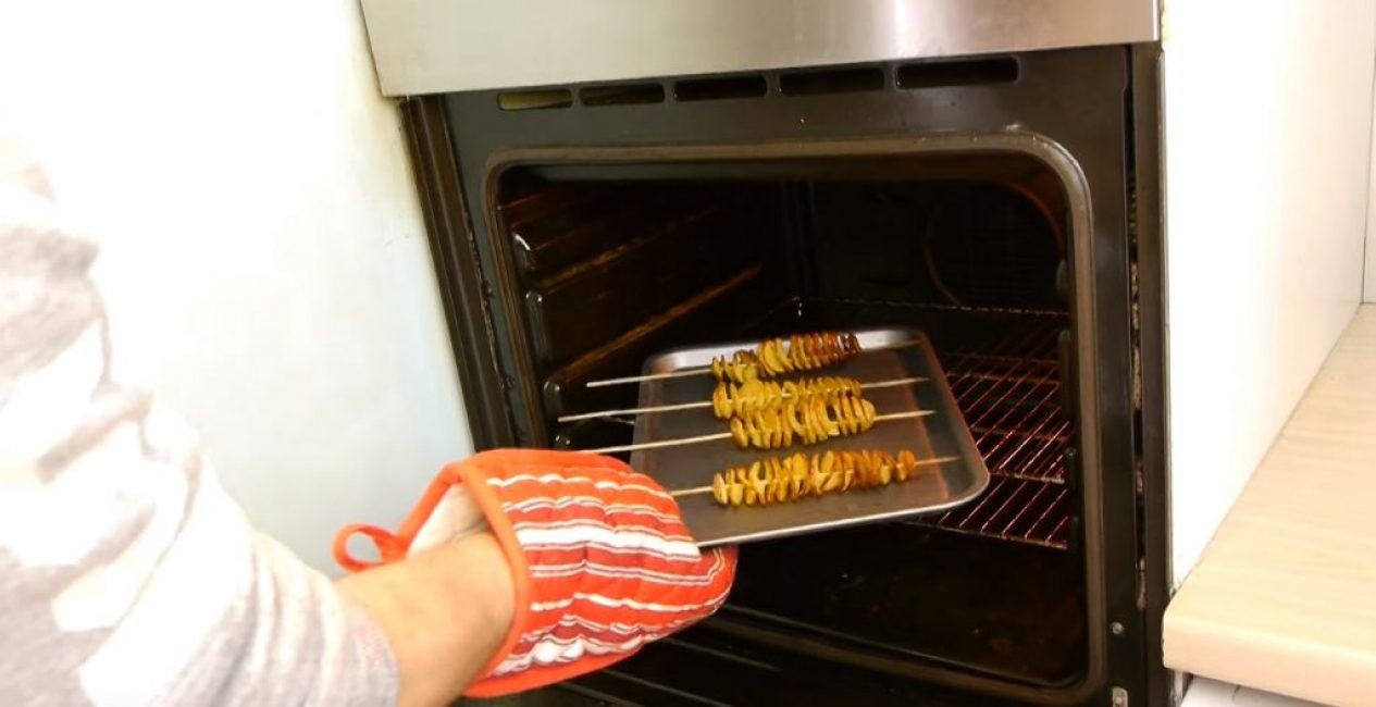Противень достают из духовки при помощи рукавицы-прихватки