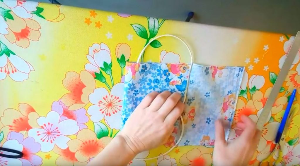 Заворачиваем сначала левую часть тканевого прямоугольника, а затем правую