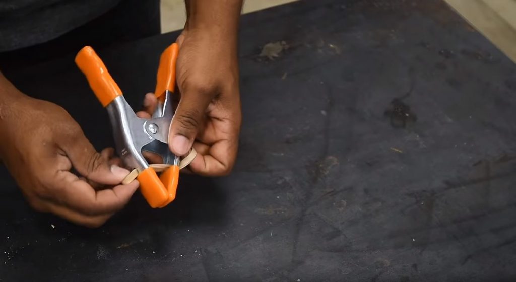 В нижней части зажима просверливаем два отверстия и протягиваем через них резиновое кольцо