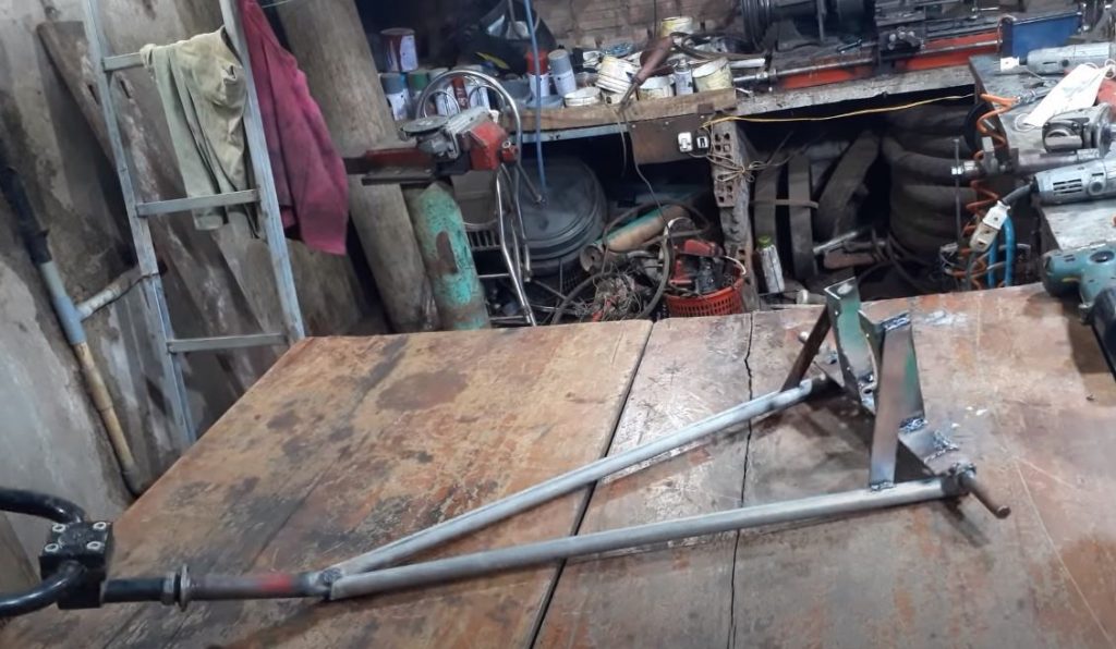 Из уголков, металлических труб, кругляка и велосипедного руля свариваем раму траншеекопателя