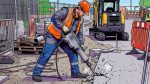 Рабочий в каске и наушниках разбивает бетон отбойным молотком на стройплощадке